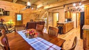 Ein Holzinterieur mit Esstisch, Stühlen, einer Treppe und einer Küchenzeile.