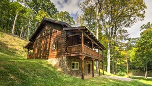 Eine Holzhütte mit steinernen Fundamenten, einem Balkon und einer Veranda.