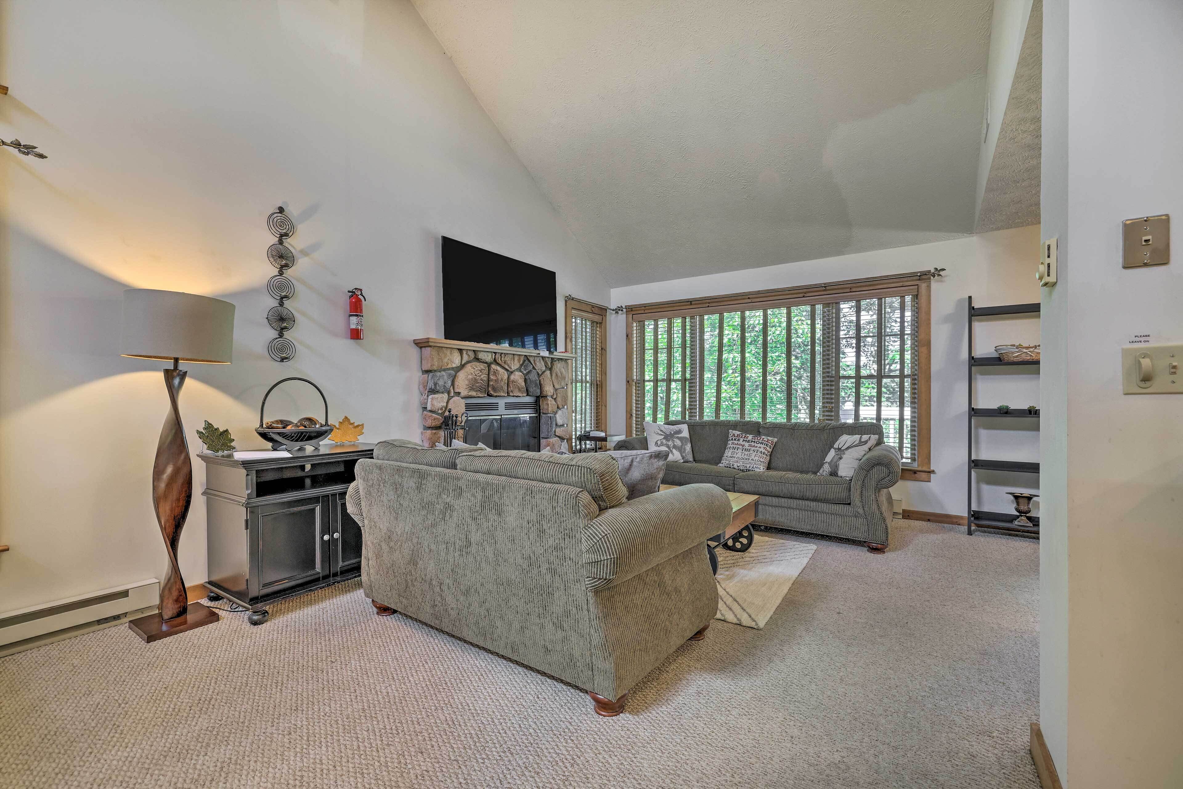A living room with a sofa, a coffee table, a lamp, a fireplace, and a window with blinds.