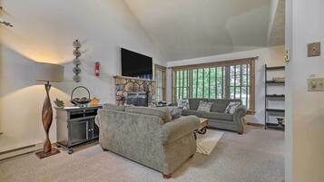 A living room with a sofa, a coffee table, a lamp, a fireplace, and a window with blinds.