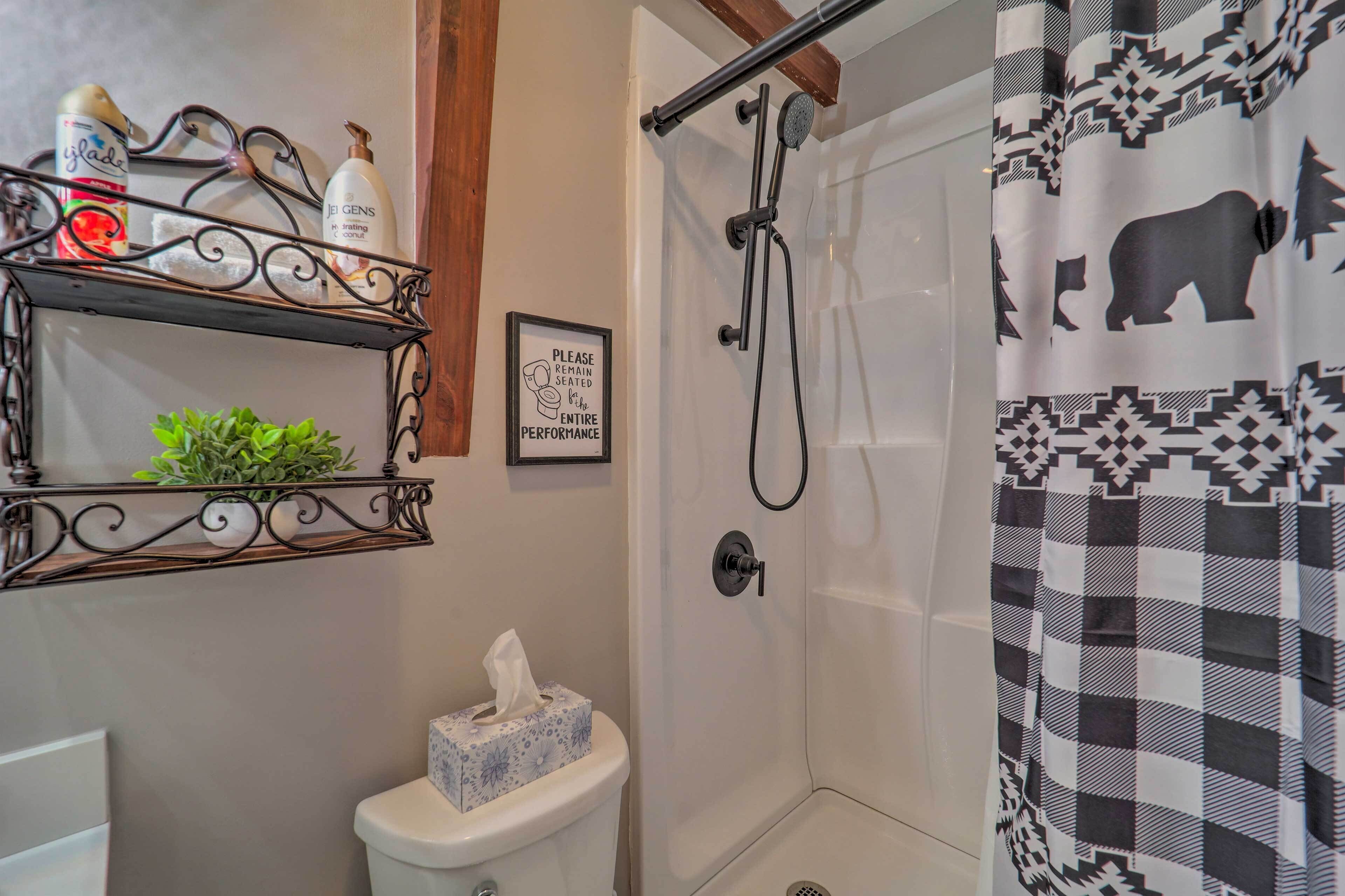 Une salle de bain équipée d’une douche, de toilettes et d’étagères où sont rangés les articles de toilette.