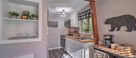 A modern kitchen with white cabinets, a wooden island, and a bear decoration on the wall.