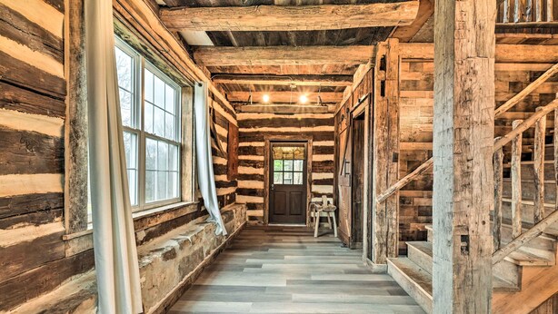 A log cabin interior with a central staircase, wooden walls, and a tiled floor. - New Paris Cabin ~ 11 Mi to Shawnee State Park (New Paris)