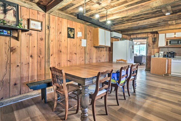 A wooden-paneled dining area with a large table, chairs, and a bench.