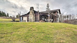 A rustic log cabin with a stone chimney, a porch, and a small attached building. - New Paris Cabin ~ 11 Mi to Shawnee State Park (New Paris)