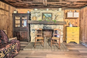 Una habitación rústica con chimenea de piedra, muebles de madera y un aparador amarillo.