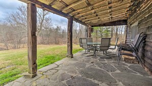 A covered outdoor seating area with stone flooring and wooden beams, overlooking a grassy landscape. - New Paris Cabin ~ 11 Mi to Shawnee State Park (New Paris)