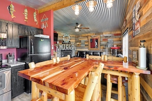 Une cuisine rustique avec une table à manger en bois, des appareils électroménagers noirs et un ventilateur de plafond.