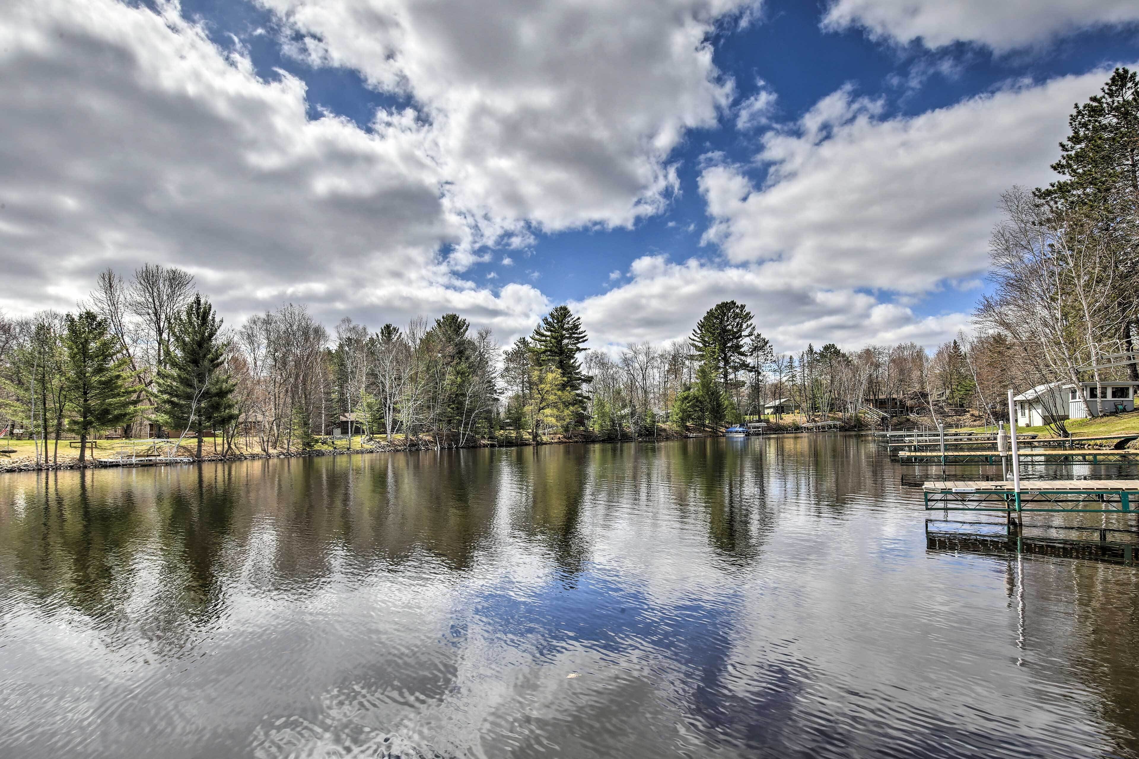 A calm lake with reflections of trees and a dock on the right.