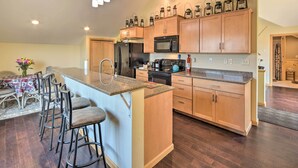 A modern kitchen with wooden cabinets, a granite countertop, and a built-in island with bar stools.