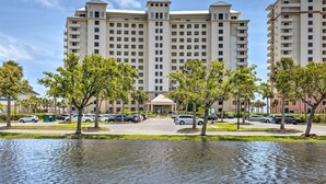 A multi-story hotel with a central entrance, surrounded by parking and trees.