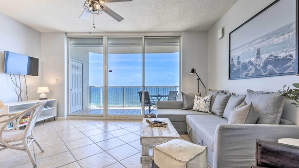 A modern living room with a sofa, coffee table, and a ceiling fan. There is a sliding glass door leading to a balcony.