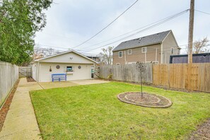 A backyard with a wooden fence, a blue bench, and a small garden area. - Family Apartment w/ Deck + Yard Near Northwestern (Evanston)
