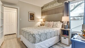 A bedroom with a bed, bedside tables, a nightstand, a window with curtains, and a door. - Family Apartment w/ Deck + Yard Near Northwestern (Evanston)