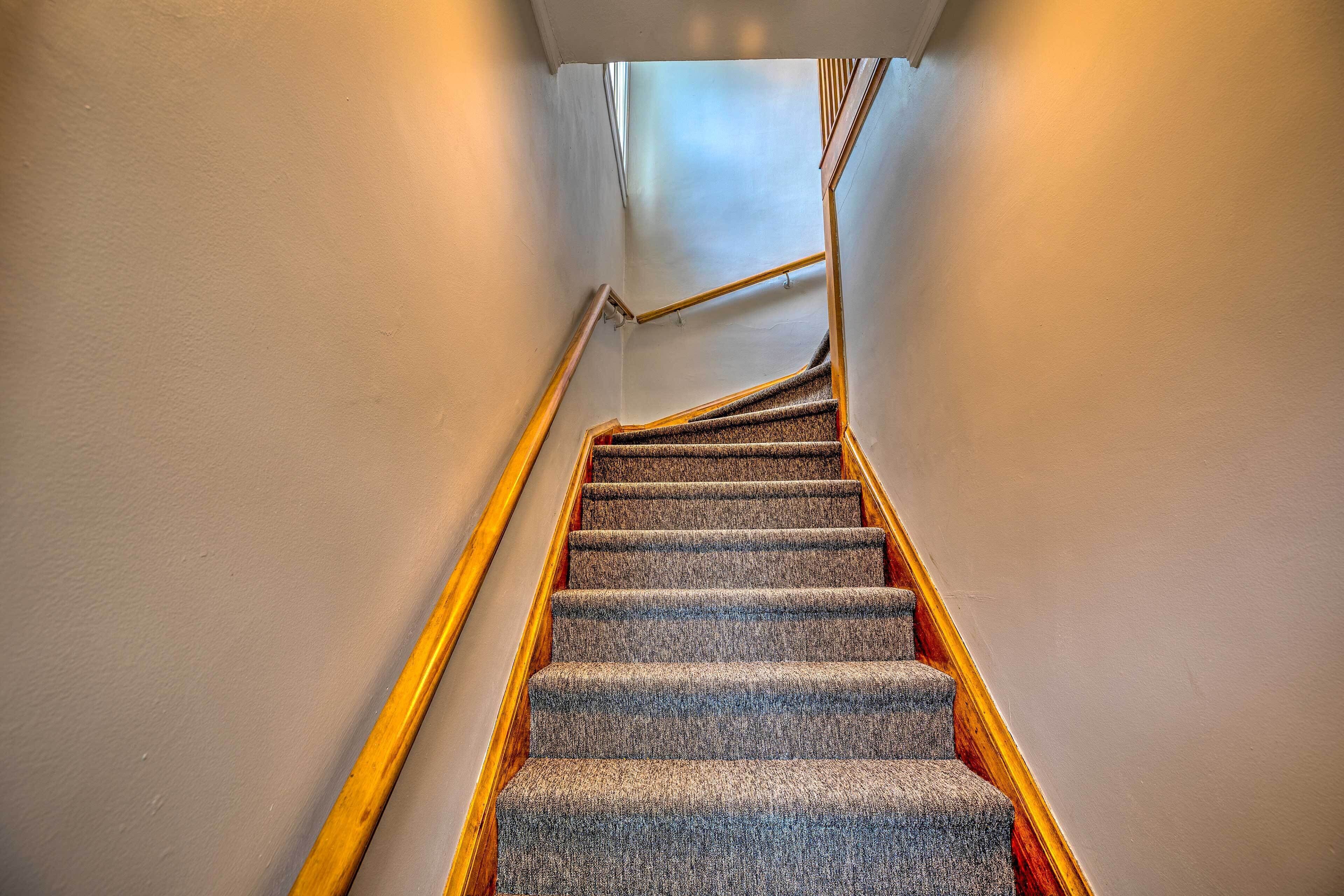A carpeted staircase with wooden handrails and a white wall.