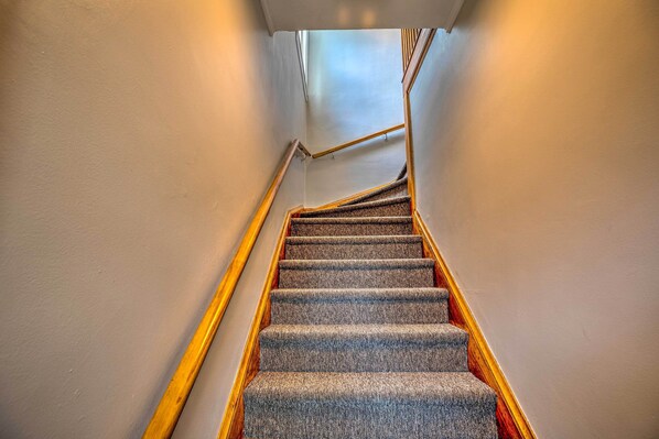 Una escalera alfombrada con barandillas de madera y una pared blanca.
