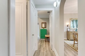 A hallway with a wooden floor, a green dresser, and a chair. - Family Apartment w/ Deck + Yard Near Northwestern (Evanston)