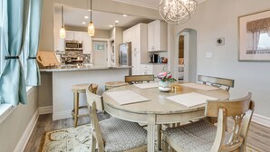 A dining area with a round wooden table, six chairs, and a chandelier. - Family Apartment w/ Deck + Yard Near Northwestern (Evanston)