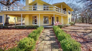 Une maison jaune à deux étages, dotée d’un porche et d’un balcon au deuxième étage.