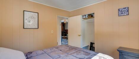 Un dormitorio con cama, cómoda, un cuadro enmarcado y un cartel en la pared.