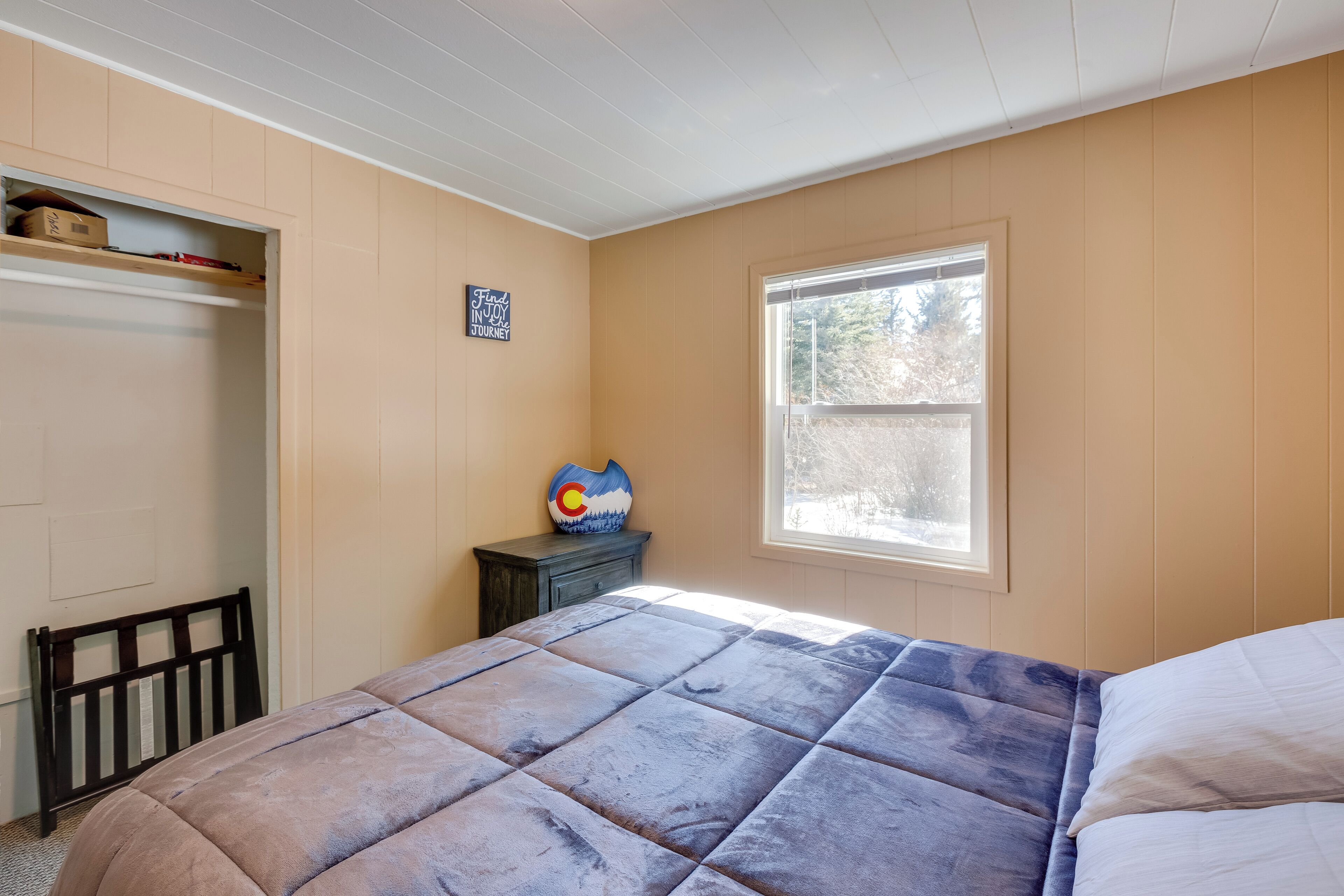 Une chambre à coucher comprenant un lit, une fenêtre, une commode et une étagère fixée au mur.