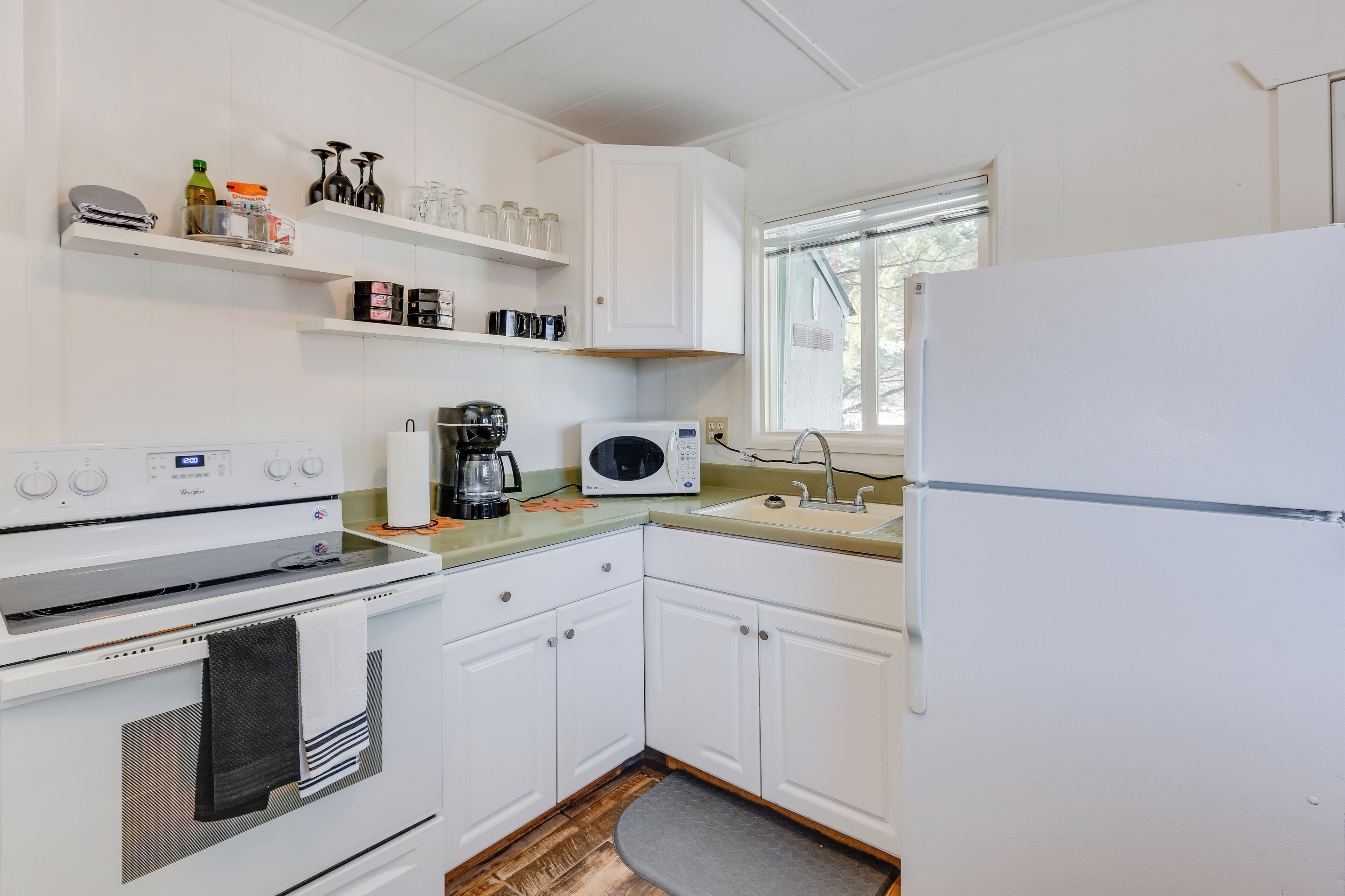 A compact kitchen with white cabinets, a microwave, a coffee maker, and a refrigerator.