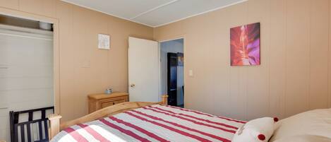 A bedroom with a bed, a dresser, a door, and a wall with a painting.
