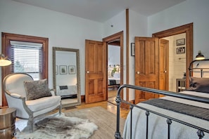 A bedroom with a bed, a chair, a fur rug, wooden doors, and a mirror.