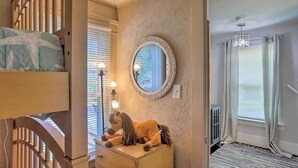 Une chambre avec un lit superposé, une commode, un miroir et un jouet en peluche.