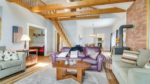 Un salón espacioso con una escalera de madera, una chimenea y una zona de estar acogedora.