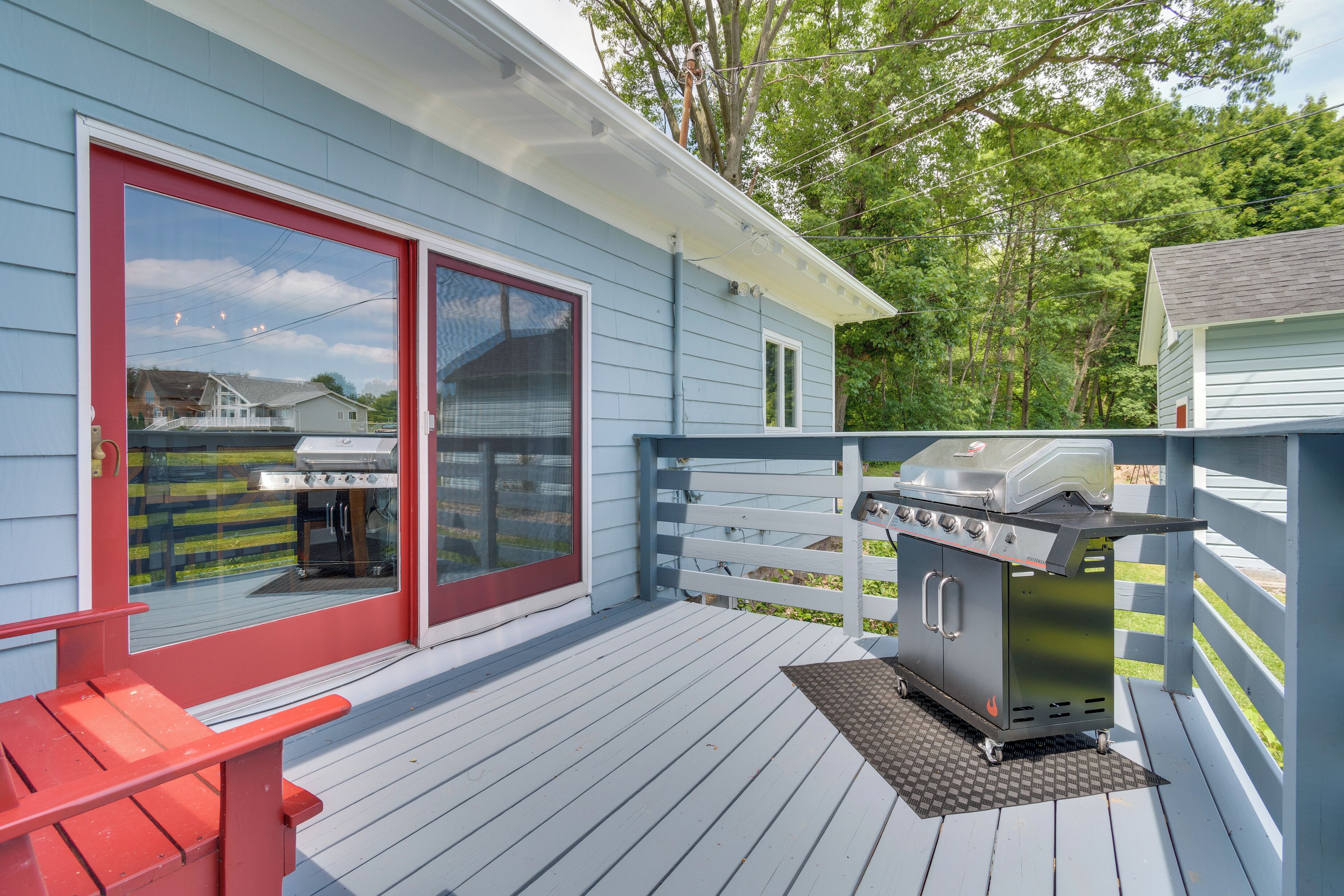 A deck with a grill, a red bench, and a sliding glass door.