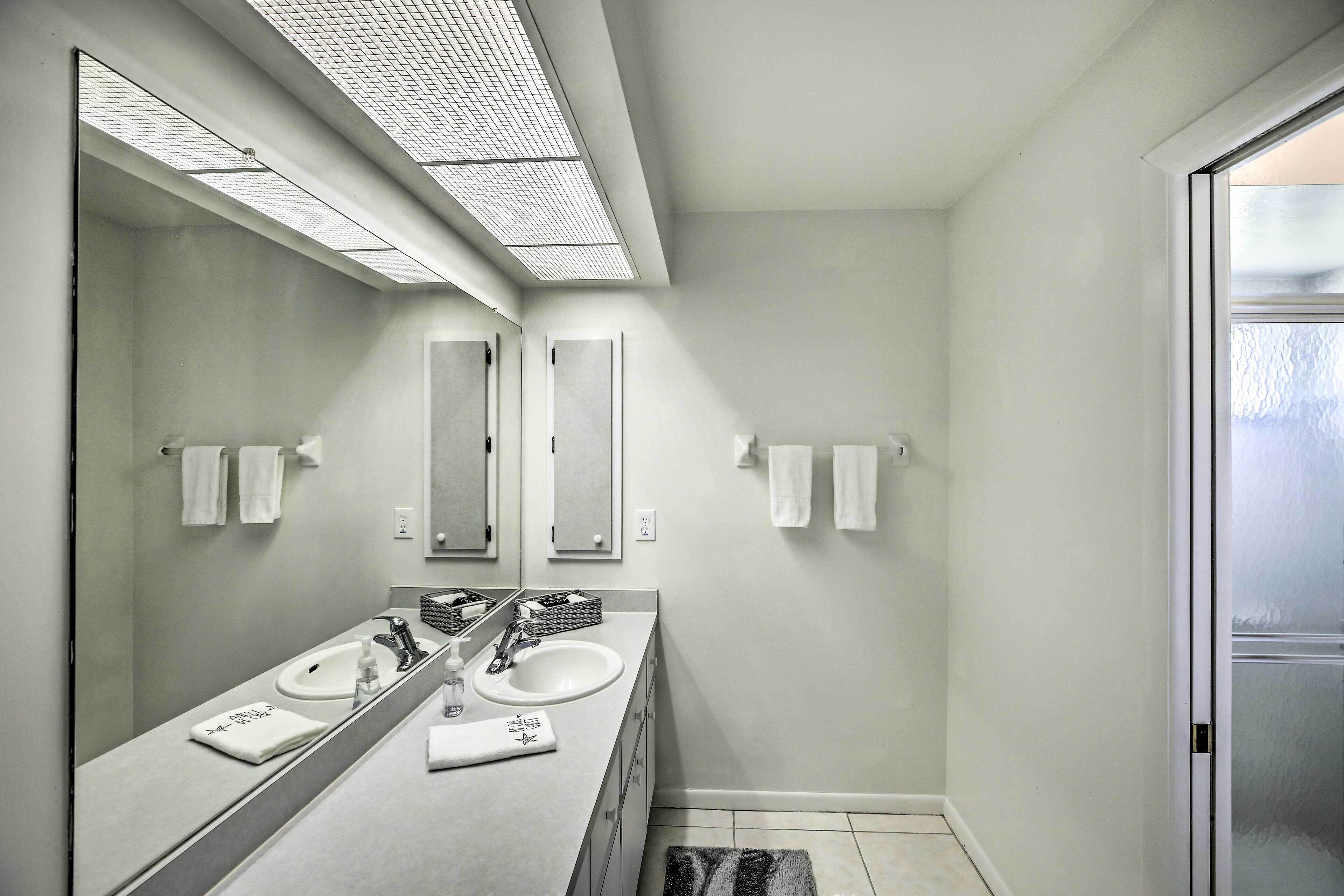 Un baño moderno con dos lavamanos, un espejo grande y una lámpara en el techo.