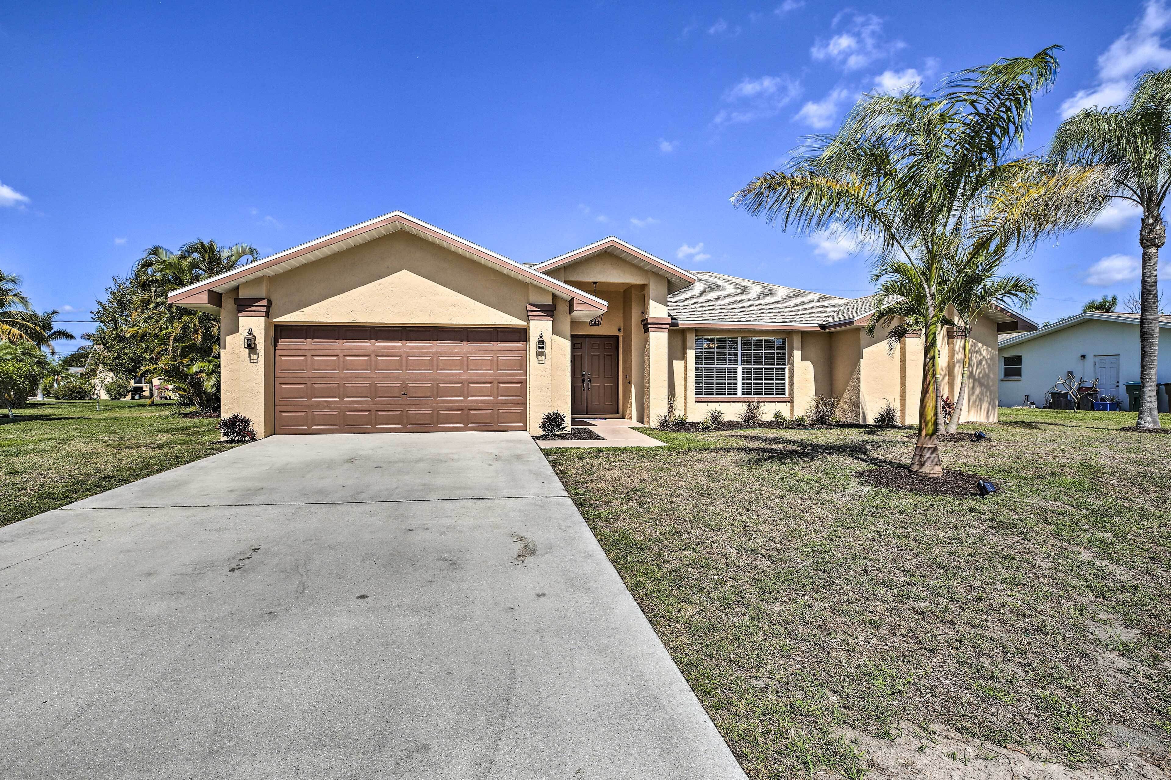 A single-story house with a brown garage, a front entrance, and a small front yard with a palm tree.