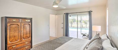 A bedroom with a bed, a wardrobe, a ceiling fan, and a view of the outside.