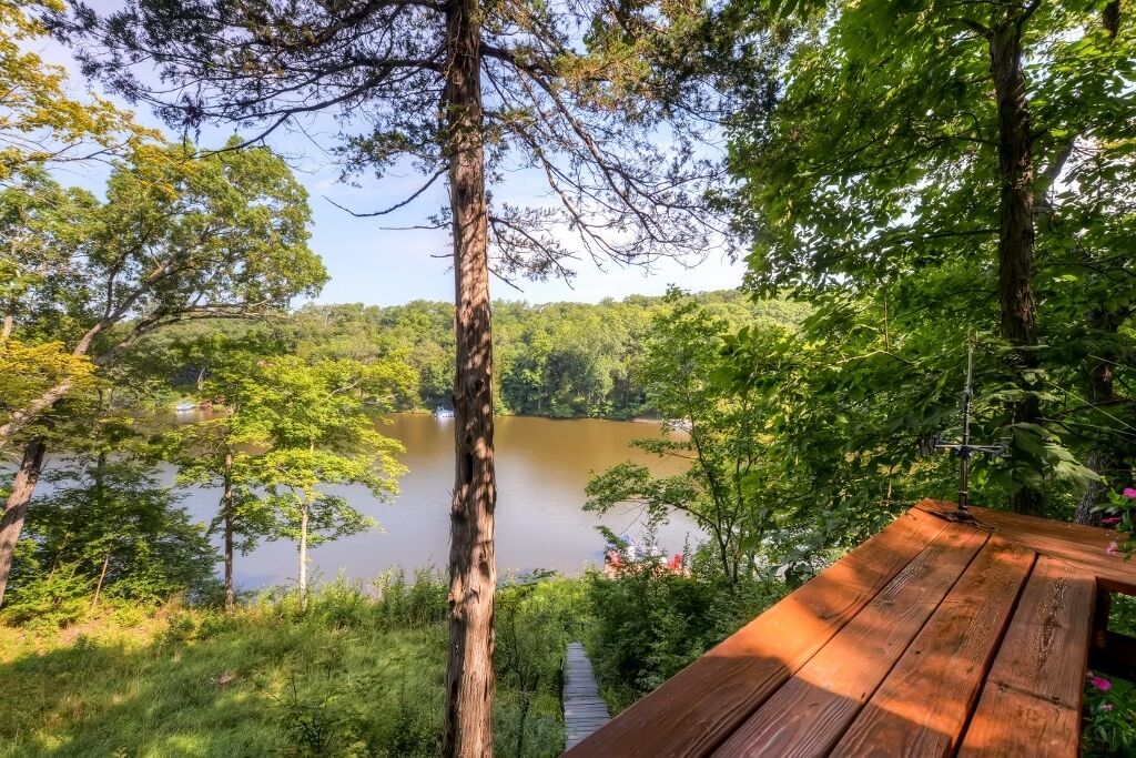 A wooden deck overlooking a lake surrounded by trees.