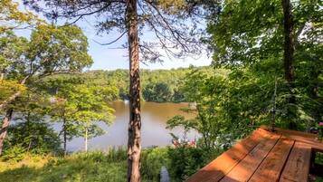 A wooden deck overlooking a lake surrounded by trees.