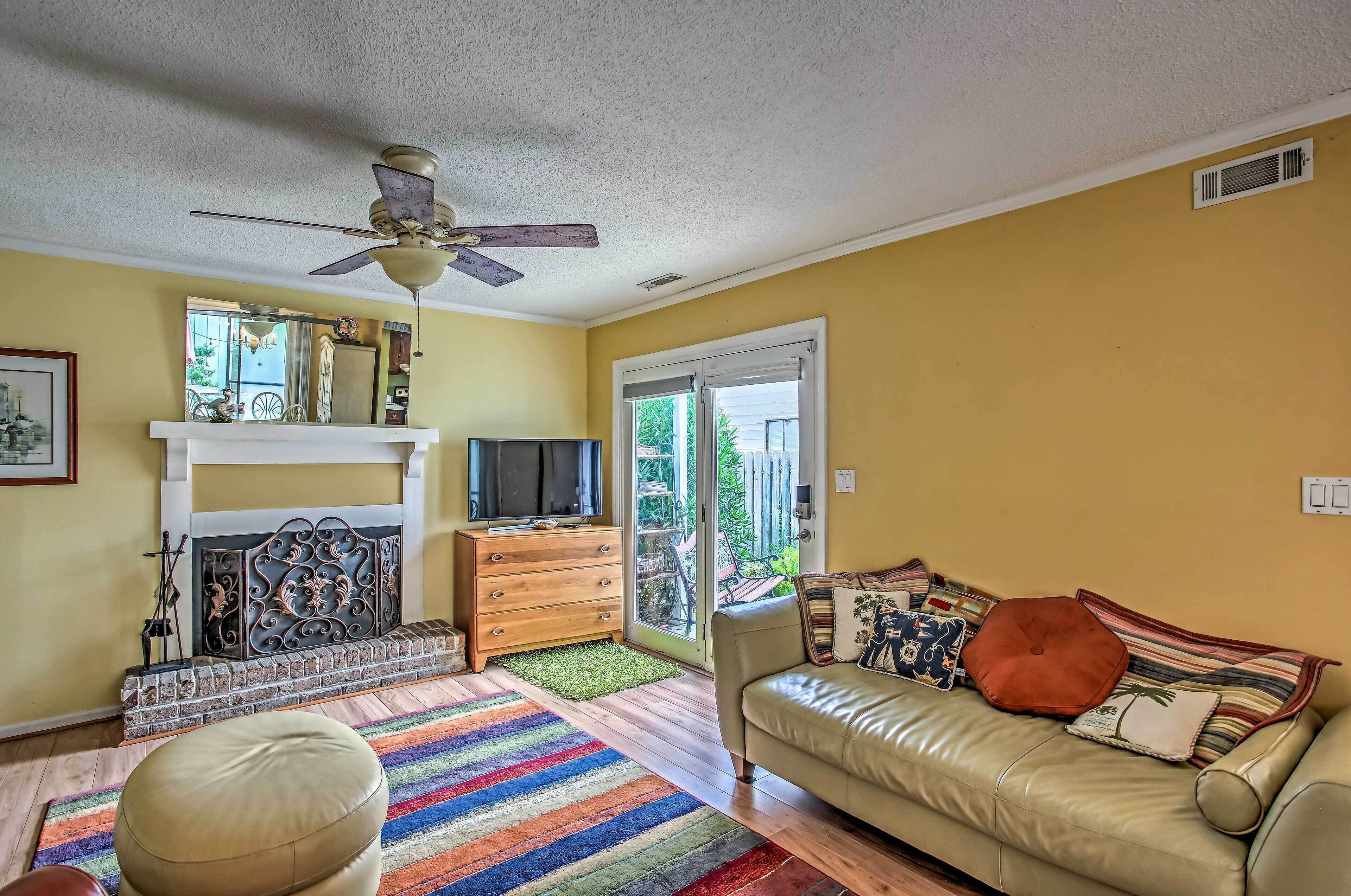 A living room with a fireplace, a sofa, a television, and a ceiling fan.