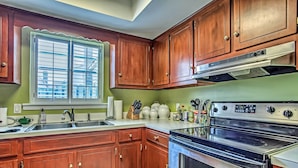 Una cocina con armarios de madera, una estufa de acero inoxidable y una ventana con persianas.