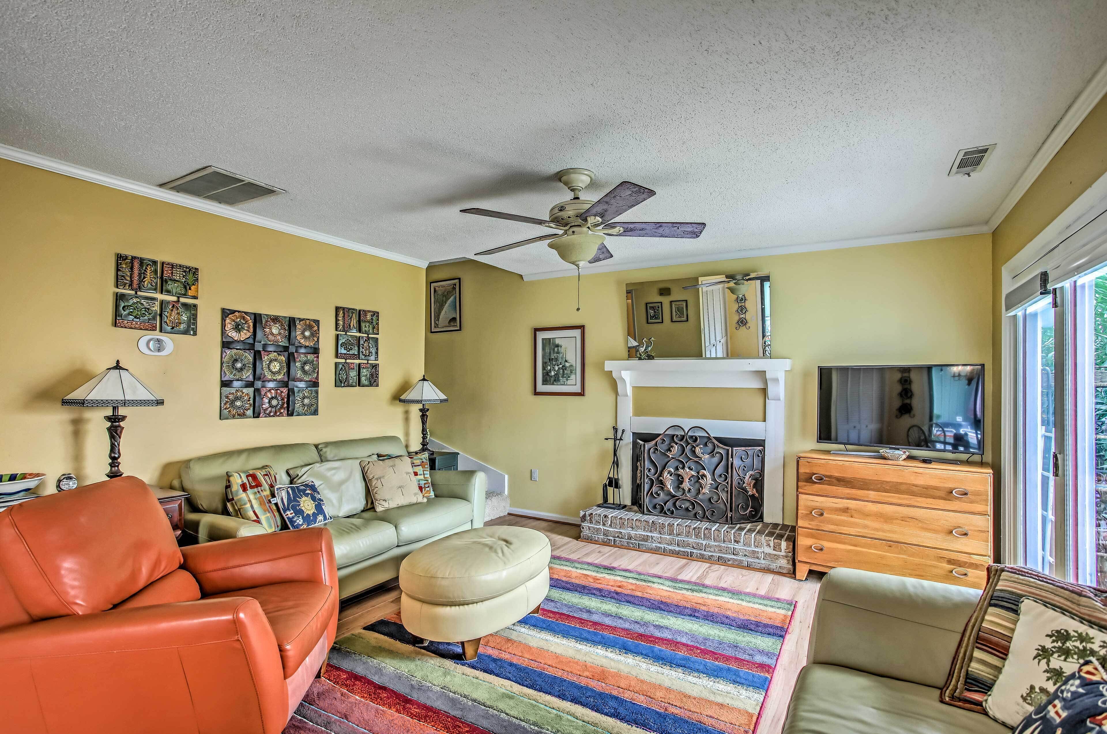A living room with a sofa, ottoman, and a fireplace.