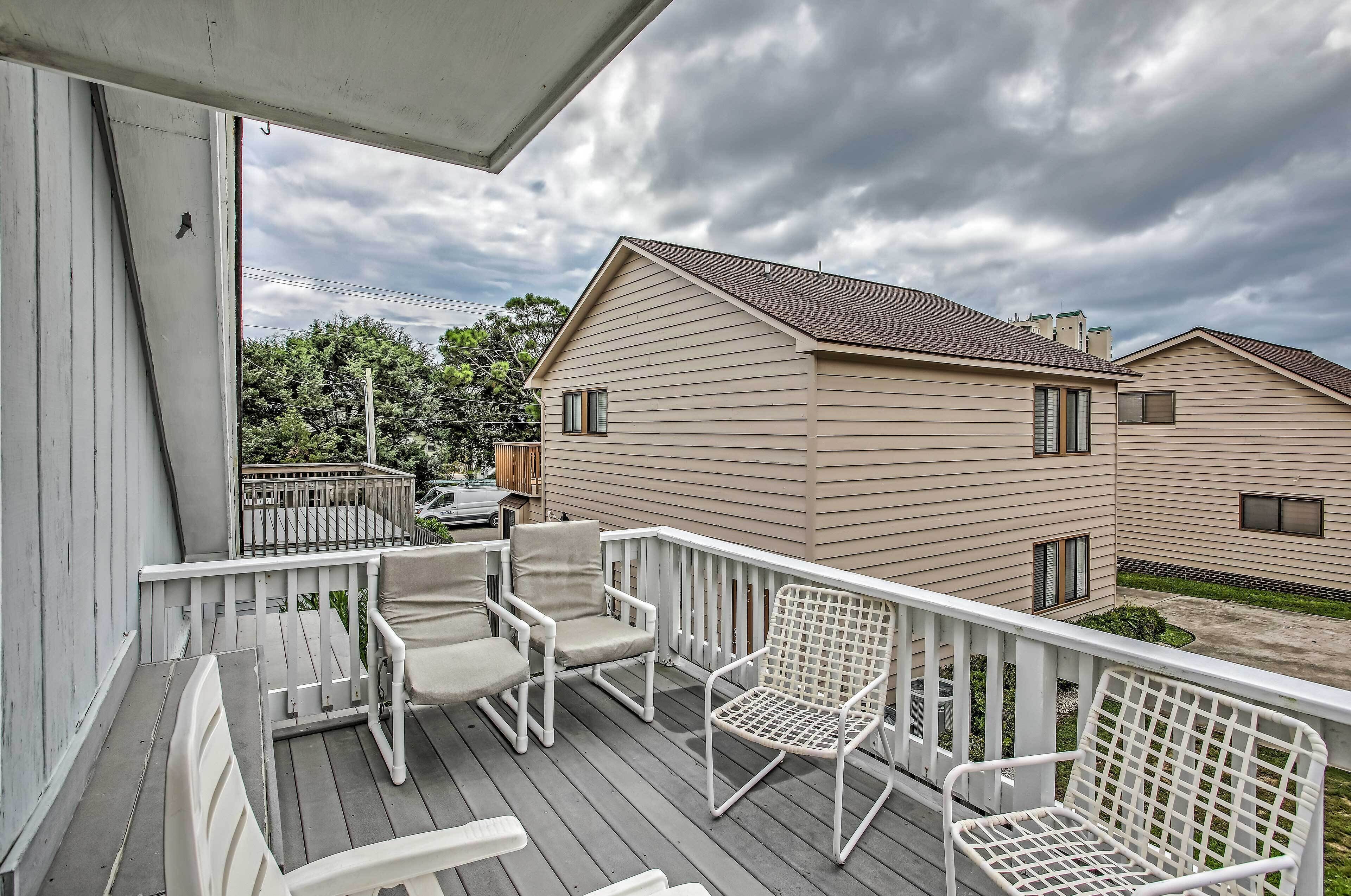 A balcony with white chairs and a white railing.