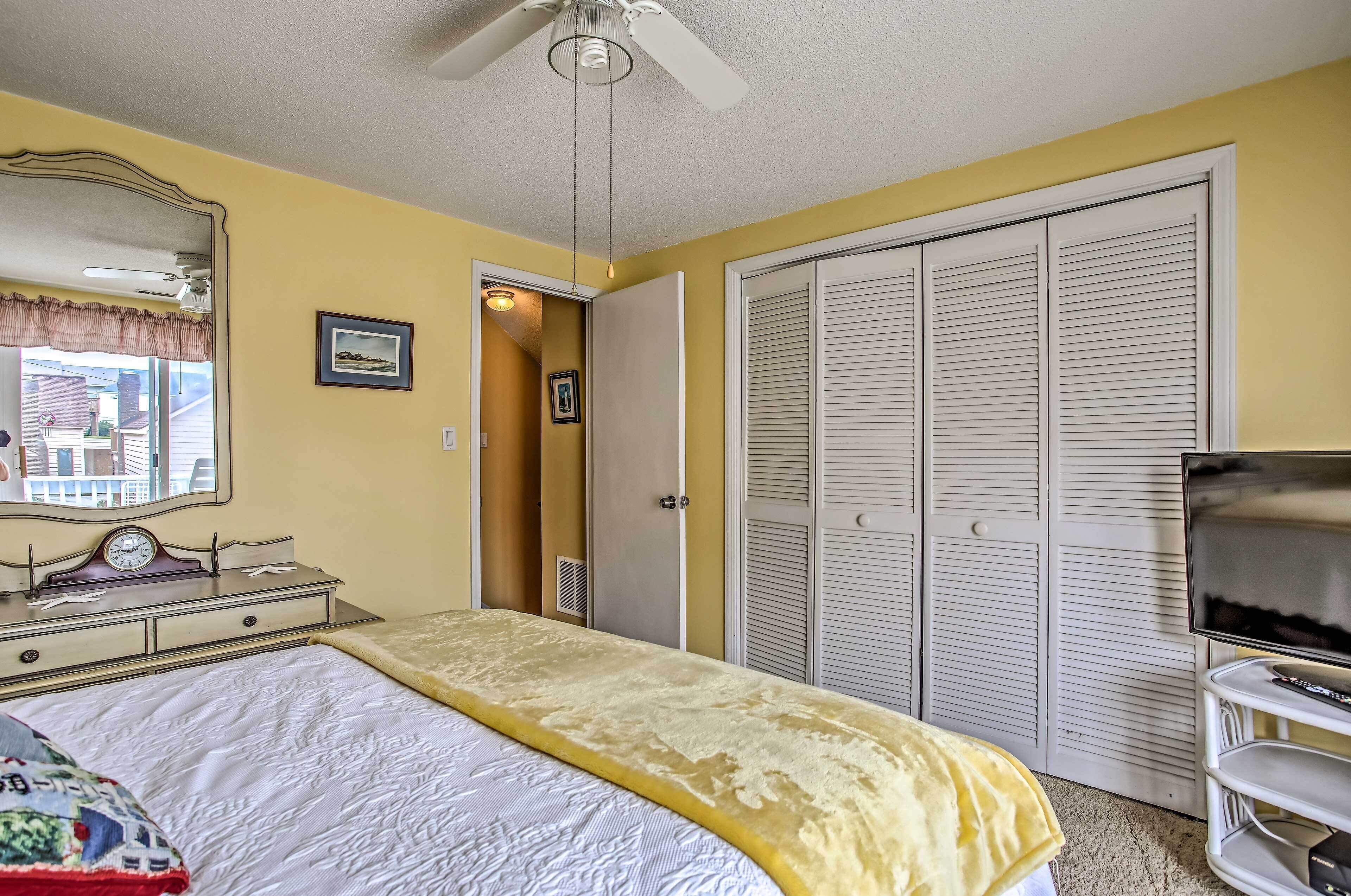 A bedroom with a bed, a dresser, a mirror, a television, and a closet.