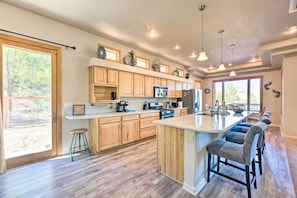 A spacious kitchen with wooden cabinets, a large island with bar stools, and a view of the outdoors.