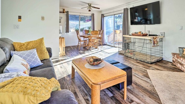 A living room with a sofa, coffee table, and TV. There is a dining area with a table and chairs. A cage with a bird is visible.