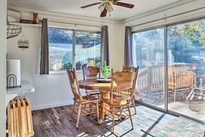 A dining area with a round table and four wooden chairs, large windows, and a ceiling fan. - Game Room & Mtn Views: Tuolumne Hideaway! (Tuolumne)