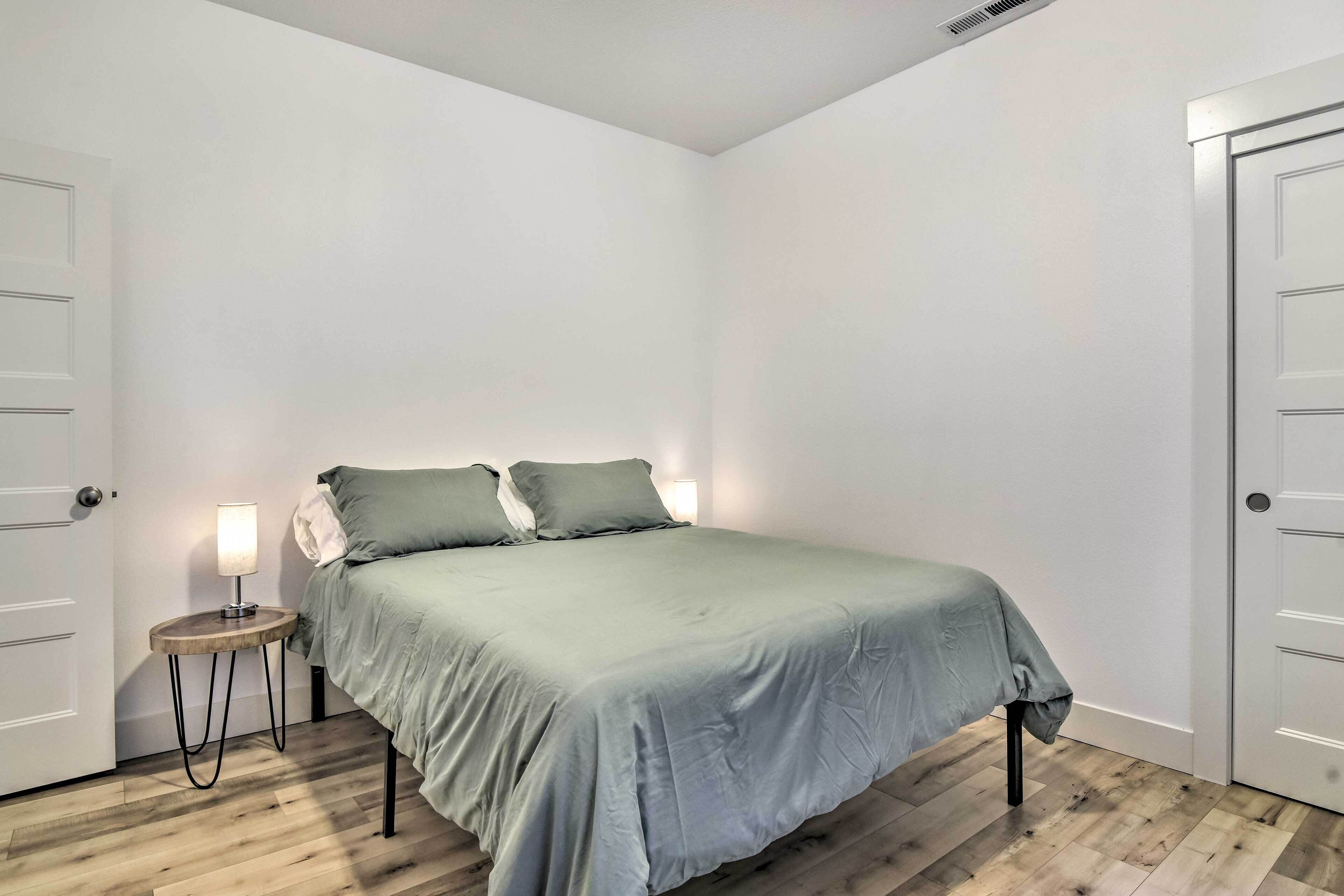 A bedroom with a bed, a bedside table with a lamp, and two doors.