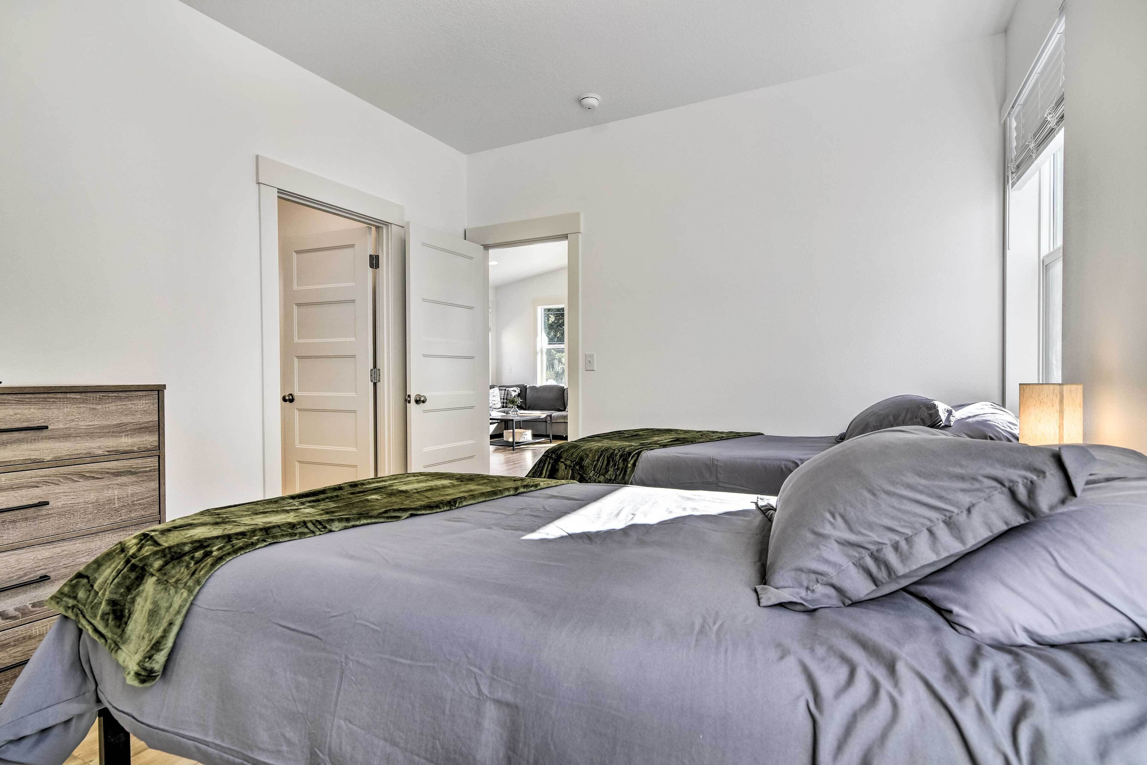 Een slaapkamer met twee bedden, een kaptafel en een deur naar een andere kamer.