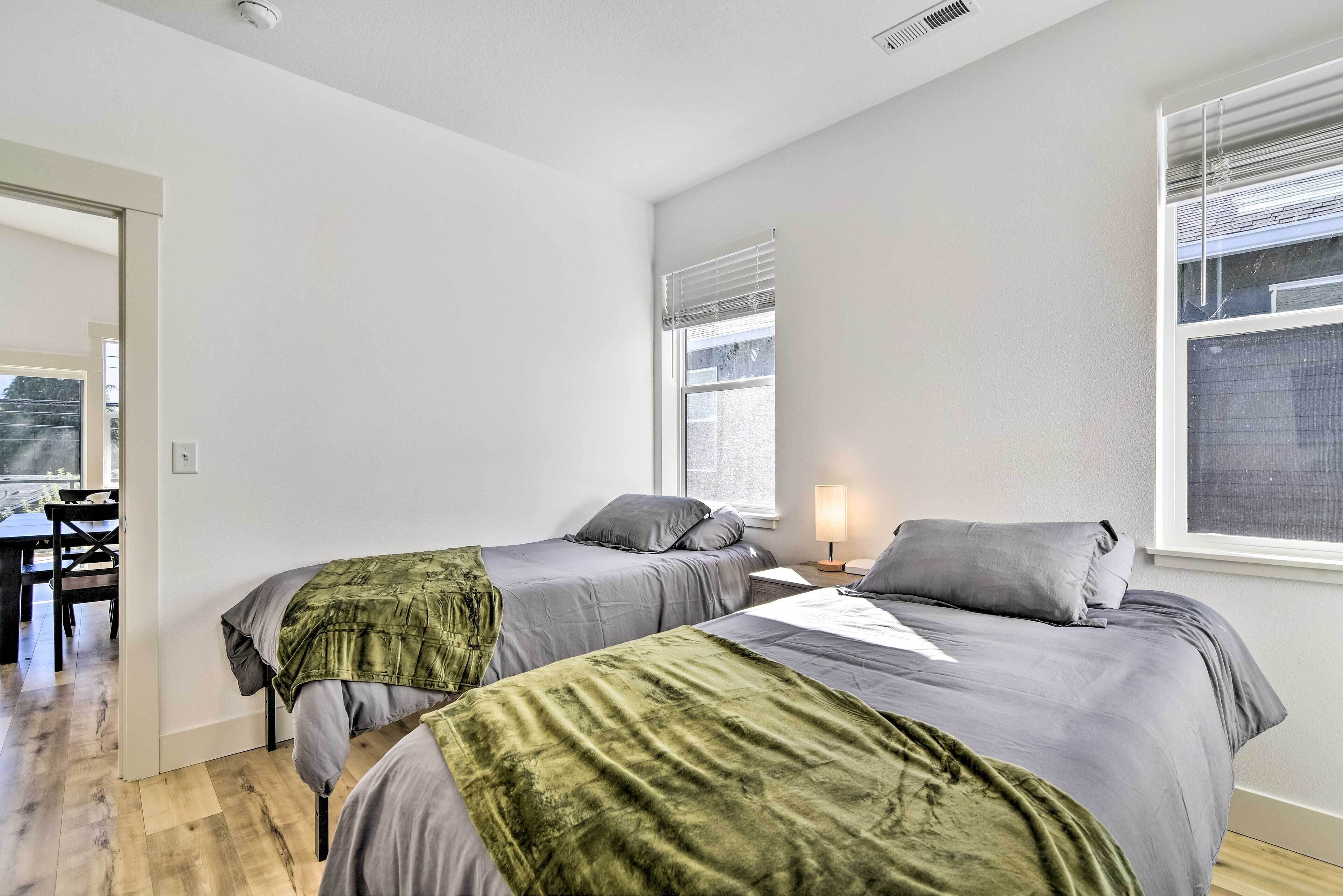 A bedroom with two beds, a desk, and a chair.