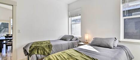 A bedroom with two beds, a desk, and a chair.