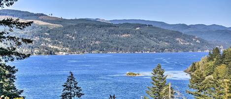 A coastal landscape with a clear view of a large body of water, surrounded by dense forests and hills.