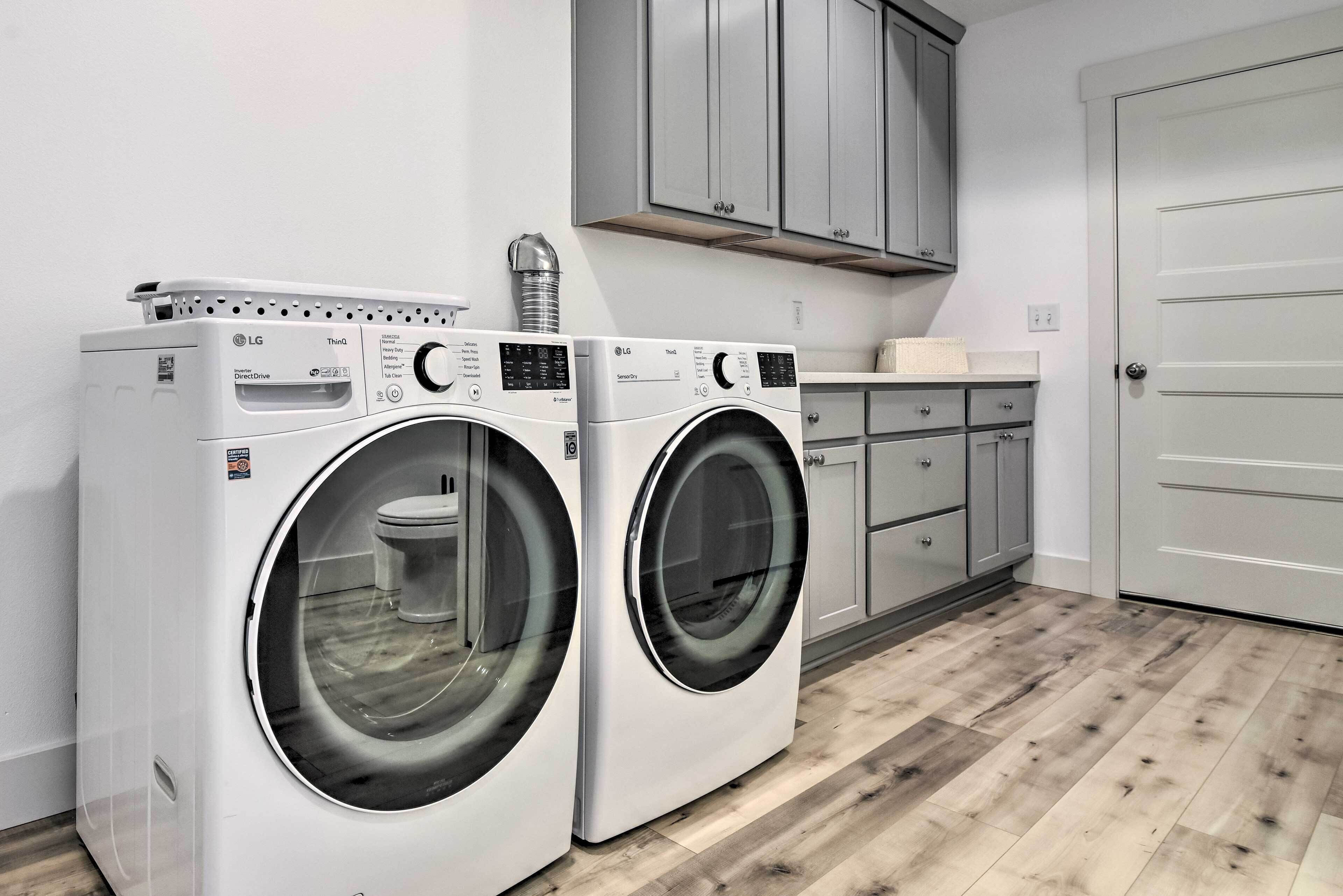 A laundry room with two white LG front-loading washing machines, grey cabinets, and a white door.